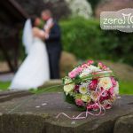 Brautstrauß auf einem Stein, Hochzeitspaar im Hintergrund